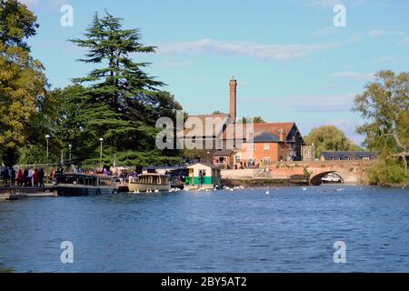Vue sur la rivière Avon jusqu'à Cox's Yard et le pont de tramway à Stratford-upon-Avon, avec des bateaux à passagers et des bâtiments historiques au bord de la rivière. Banque D'Images
