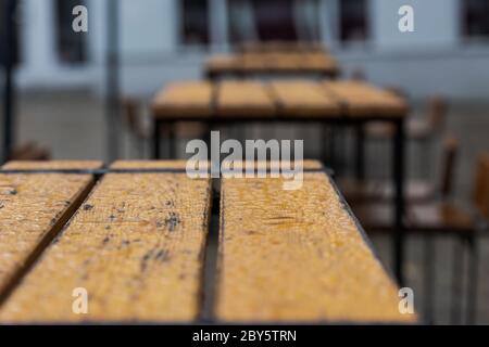 Les jours de pluie, les tables et chaises en bois vintage vides et humides sont situées dans le coin salon extérieur fermé du bar à hamburgers Banque D'Images
