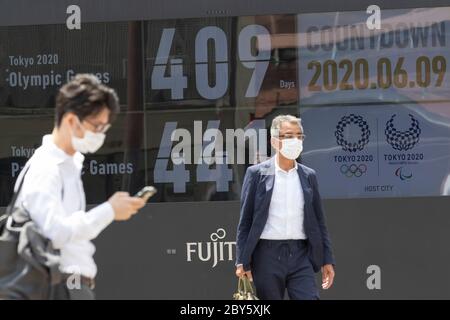 Tokyo, Japon. 9 juin 2020. Les piétons portant des masques de visage marchent devant un écran affichant un compte à rebours pour les Jeux olympiques et paralympiques de Tokyo de 2020 le 9 juin 2020, Tokyo, Japon. Un membre du conseil exécutif de Tokyo 2020 a déclaré (vendredi dernier) que les organisateurs devraient surveiller la situation de la COVID-19 jusqu'au printemps prochain avant de décider s'il faut aller de l'avant avec les Jeux olympiques et paralympiques d'été. L'horloge indique 409 jours pour les Jeux Olympiques de Tokyo 2020. Credit: Rodrigo Reyes Marin/AFLO/Alay Live News Banque D'Images