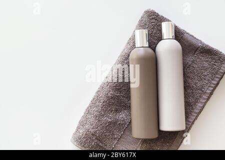 Bouteilles en plastique de shampooing et gel corporel sur serviette isolée sur blanc. Pose à plat Banque D'Images