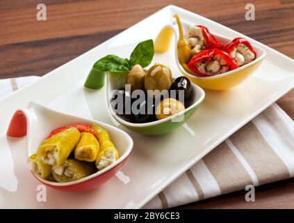 Cuisine italienne, variété d'antipasti - poivrons rouges et verts farcis au fromage de chèvre, olives noires et olives vertes aux amandes Banque D'Images