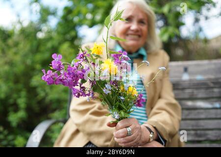 Une femme âgée tient un bouquet de fleurs colorfoul autosélectionné dans la main. Banque D'Images