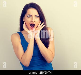 Choqué surprenant femme couvrant le visage des mains avec la bouche ouverte et les grands yeux. Portrait de gros plan vintage ton Banque D'Images