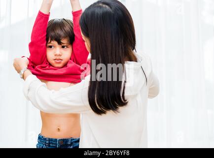 Asiatique heureuse belle mère obtenir des vêtements habillés sur ses enfants pour aller à l'école Banque D'Images