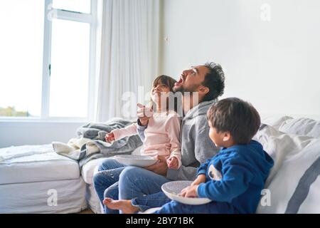 Une famille amusante qui mange du pop-corn sur son canapé Banque D'Images