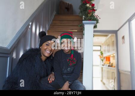 Portrait bonne mère et fils portant des chapeaux de Noël sur l'escalier Banque D'Images