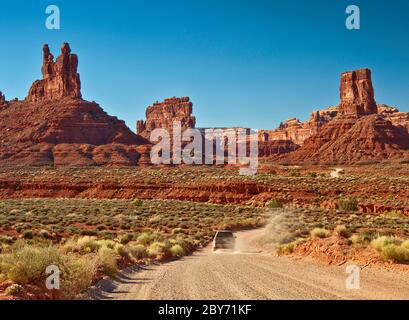 Voiture sur route de terre, formations rocheuses de grès à Valley of the Gods, monument national Bears Ears, Cedar Mesa, Utah, États-Unis Banque D'Images