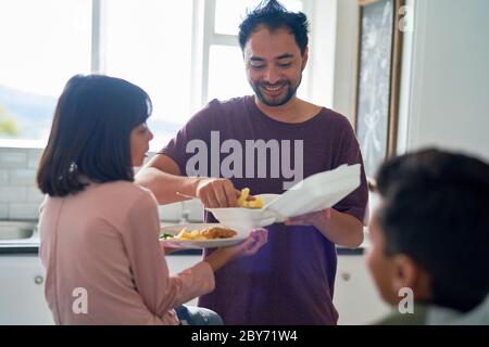 Joyeux père qui nourrit la fille à emporter dans la cuisine Banque D'Images