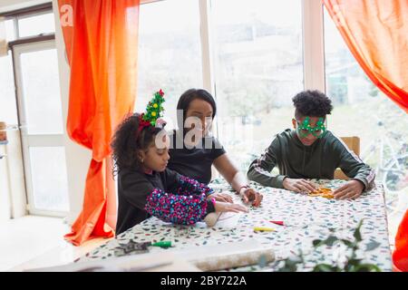 Mère et enfants qui font des biscuits de Noël à table Banque D'Images
