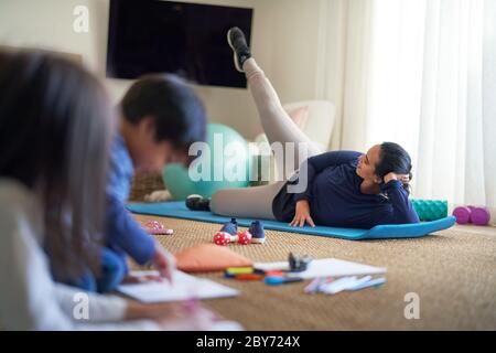 Mère s'entraînant dans le salon avec des enfants à colorier à proximité Banque D'Images
