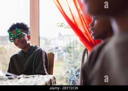 Portrait amusant garçon de fête dans des lunettes de Noël à table Banque D'Images