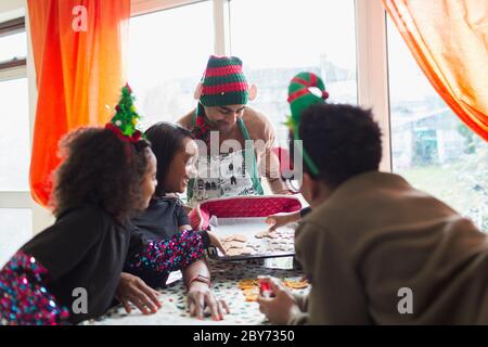 Bonne famille décorant des biscuits de Noël à la table Banque D'Images