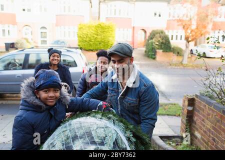 Portrait bonne famille portant un arbre de Noël dans l'allée Banque D'Images