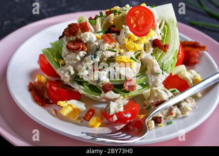 gros plan de la salade iceberg recouverte de sauce au fromage bleu, bacon croustillant, tomates cerises, œufs durs émiettés, ciboulette sur les assiettes Banque D'Images