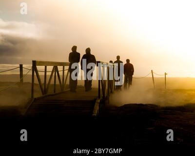 Groupe de personnes qui franchissant le pont dans la zone géothermique. Seules les silhouettes sont visibles. Banque D'Images