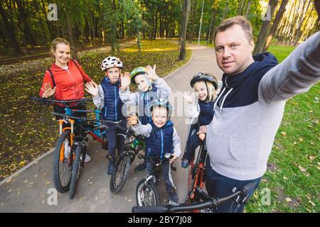 Le thème famille sports loisirs de plein air. grande famille 6 personnes de race blanche Papa maman et 4 enfants trois frères et soeur de la bicyclette dans le parc Banque D'Images