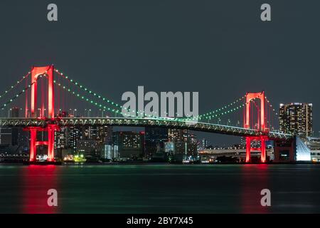 Vue nocturne du pont Rainbow, illuminé en rouge comme un signe de 'Tokyo Alert (alerte de coronavirus pour la région de Tokyo)' à Odaiba, Japon. Banque D'Images