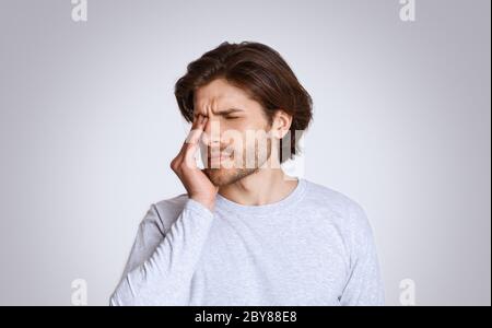 Se sentir mal à l'esprit. Guy ressent de la douleur dans ses yeux fermés et appuie la main Banque D'Images