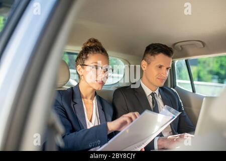 Homme d'affaires occupé avec un ordinateur portable et une femme dans des lunettes. Banque D'Images