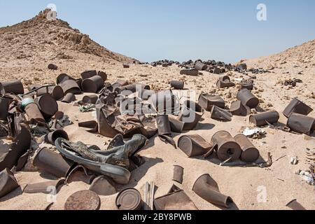 Gros plan sur la pollution des poubelles en étain dispersée et abandonnée dans un paysage désertique aride éloigné Banque D'Images