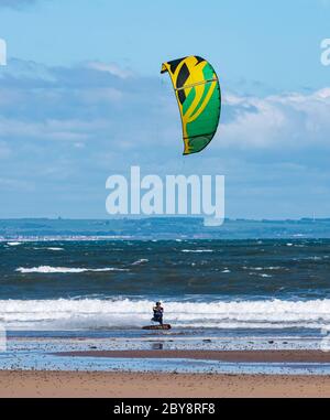 Kite surfeur ou bateau dans les vagues à Broadsands Bay le jour ensoleillé, Firth of Forth, East Lothian, Écosse, Royaume-Uni Banque D'Images