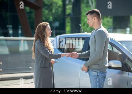 Jeune jolie femme et homme haut debout près de la voiture, homme donnant les clés de la voiture Banque D'Images