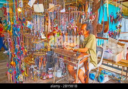 DAMNOEN SADOAK, THAÏLANDE - 13 MAI 2019 : l'artisan fabrique des souvenirs, des talismans, des accessoires et des draamcatcheurs de fils et de coquilles de cowry en décrochage Banque D'Images