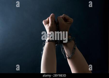 Les poings des mains sont enchaînés en chaîne sur fond noir, concept de combat et de liberté. Banque D'Images