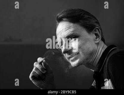 Un homme avec une cigarette. Contraste de lumière du soleil. Tabagisme et santé. Noir et blanc. Banque D'Images