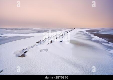 Vieux brise-lames dans la mer du Nord sous la neige Banque D'Images