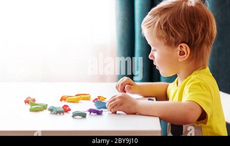 Blanc bébé blond sculpte de la pâte pour enfants pour sculpter à la maison à la table, les enfants et la créativité, le développement de fines compétences motrices. Banque D'Images