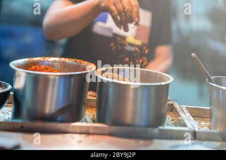 Chef chinois ajoutant des épices chaudes à la cuisine tout en cuisinant la nuit dans la rue dans le quartier musulman, ville de Xian, Chine Banque D'Images