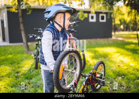 Cycliste garçon réparation de vélo. Petit garçon fixant son vélo. Mécanique des enfants, métier de réparation de bicyclettes. Apprendre à connaître les cycles et les moteurs. Petit Banque D'Images