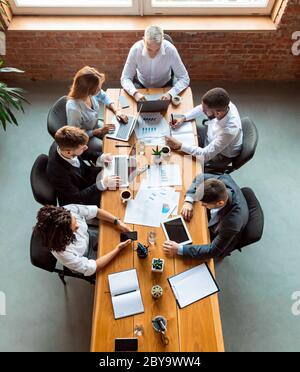 Collègues travaillant à l'aide de gadgets assis dans un bureau moderne, au-dessus de la vue Banque D'Images