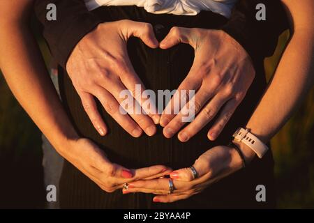 Couple enceinte dehors au coucher du soleil. Bonne grossesse familiale Banque D'Images