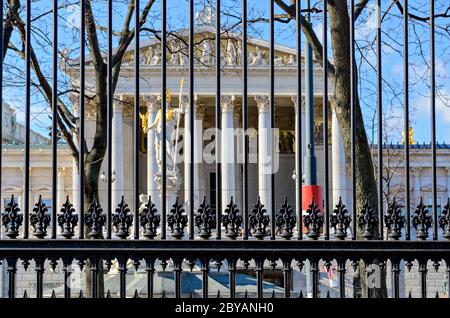 Vue à travers une clôture historique en fonte du jardin du peuple (Volksgarten) sur le Parlement à Vienne, Autriche Banque D'Images