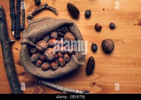 Fruits d'automne, sac de toile de jute plein de noix et noisettes sur table en bois, vue sur le dessus Banque D'Images