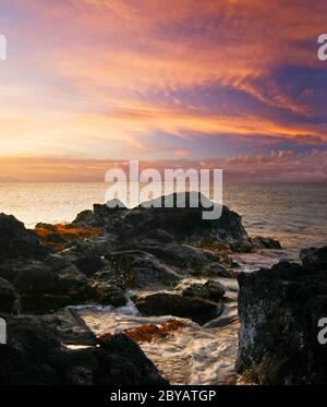 Coucher de soleil sur la plage de pierres volcaniques. Hawaï Banque D'Images