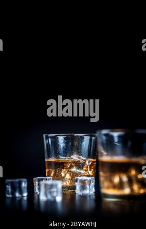 Whisky, whisky, bourbon ou cognac avec des cubes de glace sur table en pierre noire Banque D'Images