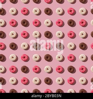 Beignets roses, vanille et chocolat avec saupoudrer, motif sans couture, dessert glacé sucré sur fond rose minimal, vue du dessus Banque D'Images