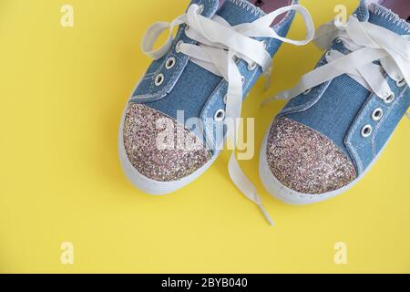 Chaussures en denim pour enfants avec lacets sur fond jaune.mode pour enfants.paire de sneakers tendance pour enfant brillantes. Bottes mode pour filles d'été.espace de copie Banque D'Images