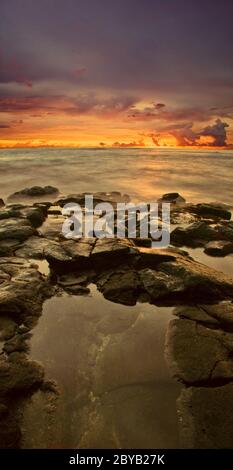 Coucher de soleil sur la plage de pierres volcaniques. Hawaï Banque D'Images