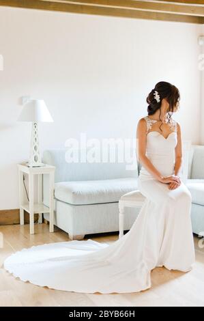 Mariée assise sur une chaise avec vue par la fenêtre Banque D'Images