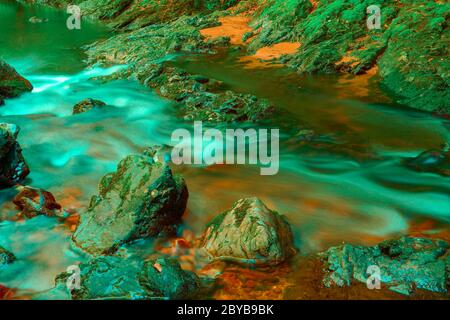Pierres dans un ruisseau avec de l'eau brouillée par une longue exposition Banque D'Images