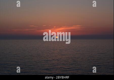 Coucher de soleil sur la mer, ciel rouge burningr avec quelques nuages, horizon et surface de mer bleu foncé, île Lefkada, Grèce Banque D'Images