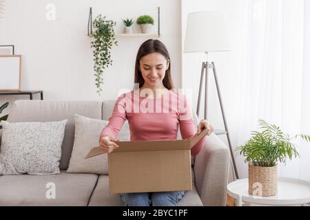 Boutique en ligne et livraison des achats. La fille a reçu une bonne commande dans la salle de séjour Banque D'Images