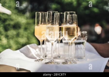 Plusieurs verres de vin blanc sur plateau. Verres de champagne Dewy. Arrière-plan extérieur. Célébration, anniversaire, fête, mariage. Banque D'Images