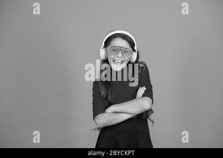 Accessoire de fête. Fille avec lunettes arrière-plan orange. Événement et divertissement. Fille de fête. Amuse-toi bien. Liste de lecture pour la fête. Concept de musique. Enfant porter des lunettes. Magasin de mode de lunettes. Piste froide. Banque D'Images