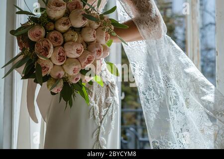 Gros plan des mains de mariée tenant beau bouquet de pivoines roses dans les mains Banque D'Images