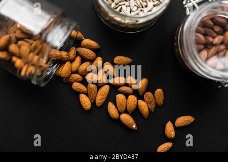 Amande dispersée sur la table noire d'un pot. Le noyer est une alimentation saine et nutritive aux protéines végétariennes. Banque D'Images